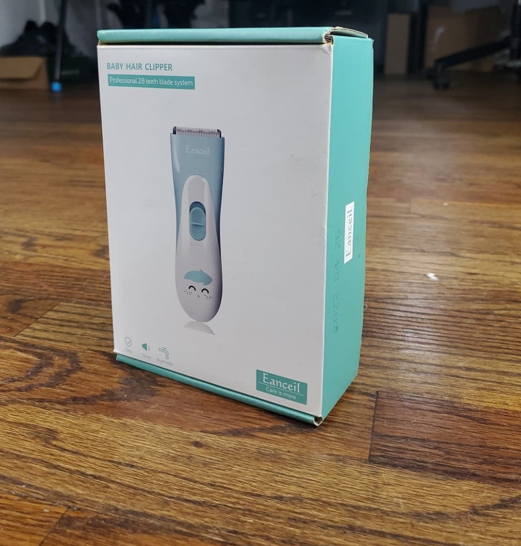 Raw phone photo of a baby hair clipper box on a wooden floor before Portrait Drop