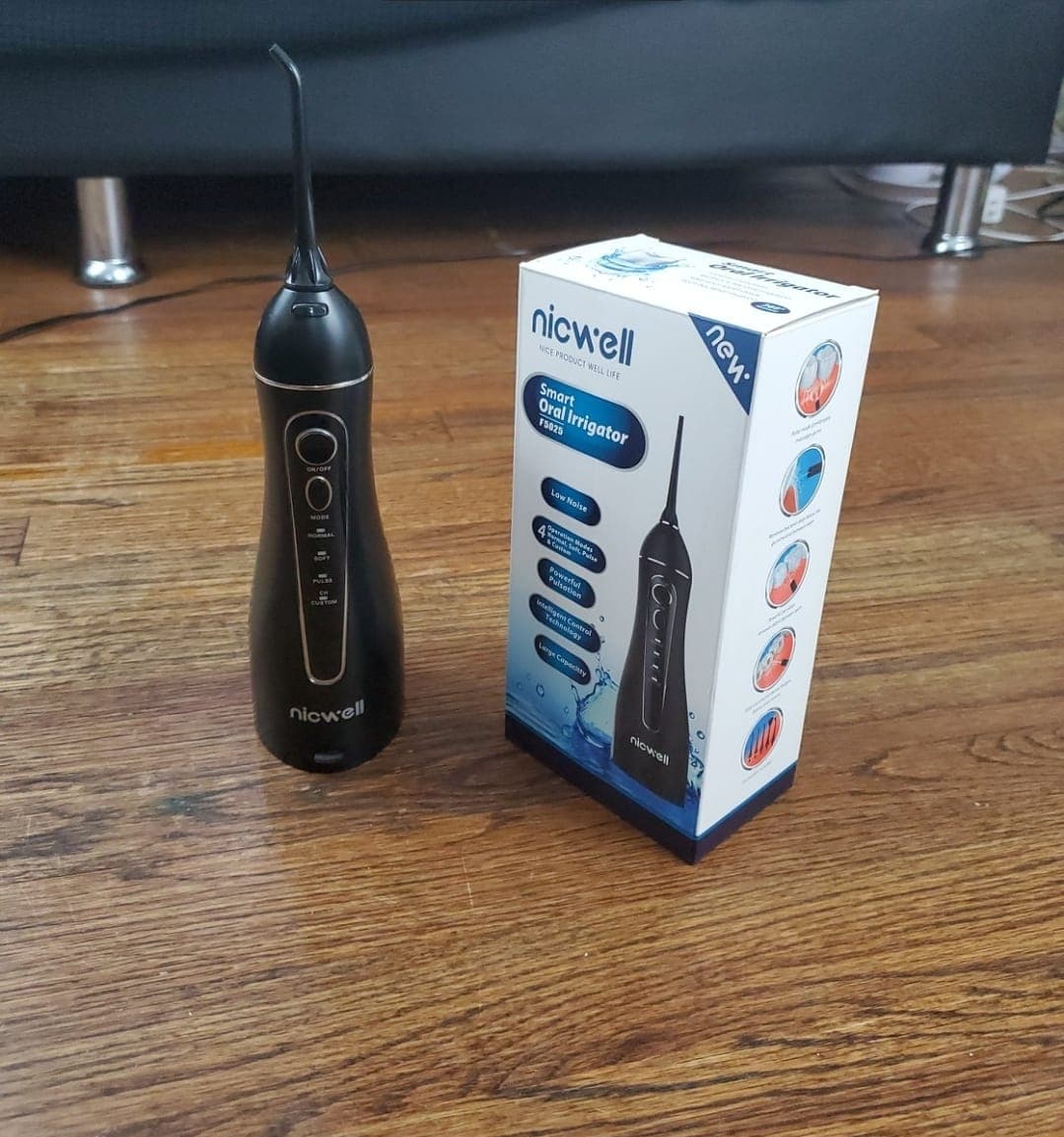 Raw Android product photo of an oral irrigator and box on a wooden floor before Portrait Drop